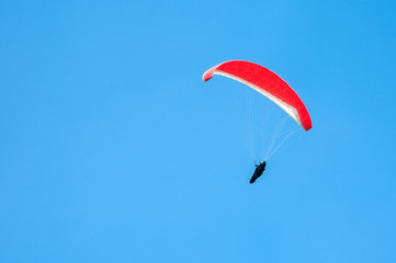 Alone paraglider flying in the blue sky. Paragliding in the sky on a sunny day.