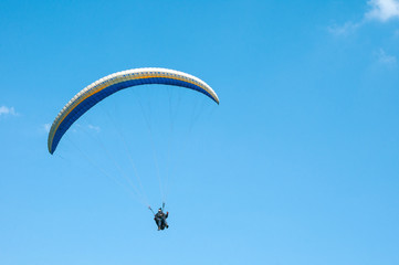 Alone paraglider flying in the blue sky. Paragliding in the sky on a sunny day.