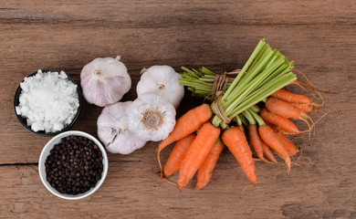 fresh carrots bunch Salt black pepper garlic   on rustic wooden background