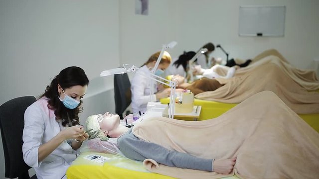 In the cosmetology room many masters increase eyelashes to young beautiful girls