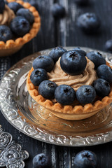 Cupcakes with cream and blueberries on a rustic background.