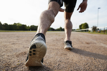 Low section of male runner&rsquo;s legs ready to run at a track