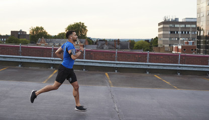 Obraz premium Young male athlete running on a road, side view