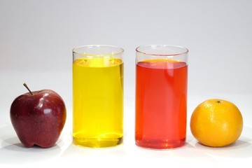 Apple and orange with yellow red glasses of juice 