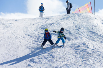 Two young children, siblings brothers, skiing in Austrian mountains on a sunny day © Tomsickova