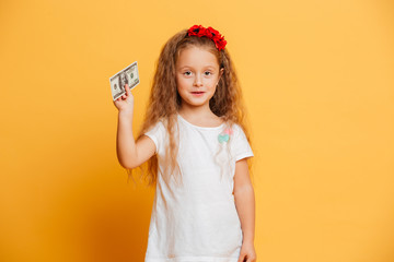 Little cute girl standing isolated holding money looking camera.