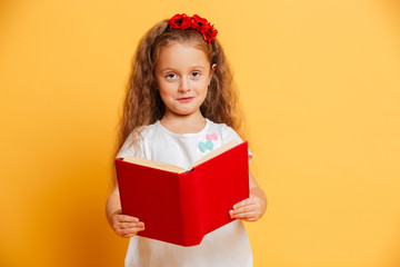 Little pretty girl reading book looking camera.