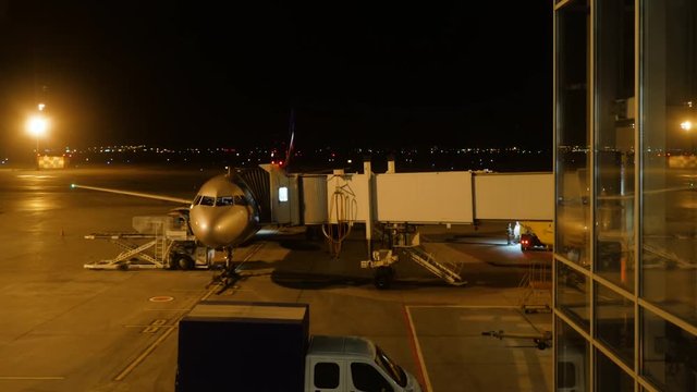 Close view of aircraft fuselage near the entering baggage door, at night. Plane takes passengers. Timelapse