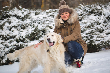 Beautiful girl playing with her dog in the snow. Golden Retriever