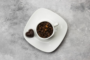 Obraz na płótnie Canvas White cups for espresso filled with coffee beans and chocolate in form of heart on a light background. Top view