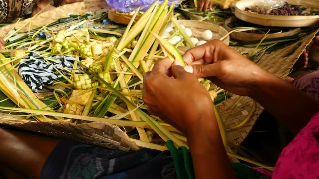 Balinese women hands make sacrificial baskets, Bali
