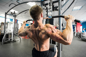 Fototapeta na wymiar Shoulder pull down machine. Fitness man working out lat pulldown training at gym. Upper body strength exercise for the upper back.
