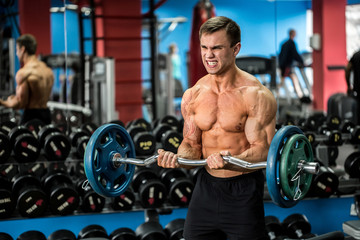 Naklejka premium Very power athletic guy standing workout in the gym
