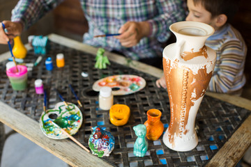 Father and son paint a vase
