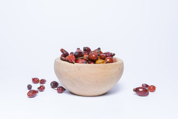 Dried dog-rose (Rosa canina) berries  in wood bowl. Health concept, natural medicine. Spreaded berries around the bowl.