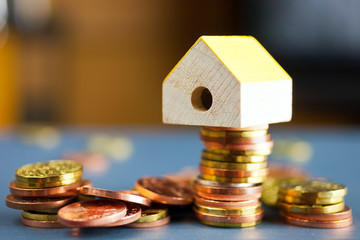 economy and finance - piles of czech crown coins with a model of house - househod expenses amd mortgage concept