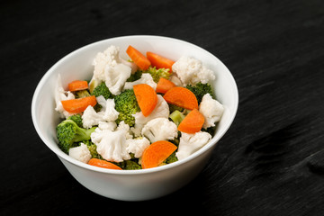 Fresh salad with raw broccoli, cauliflower and carrot in a white dish