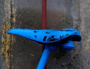 old blue bicycle saddle in front of a wall