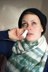 Fototapeta premium Sick girl sprays the spray from runny nose into the nasal pass