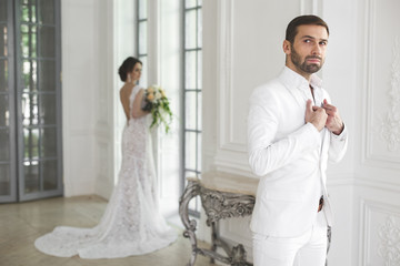 Chic wedding couple groom and bride posing in a white Studio. Happy couple laughing. White dress....