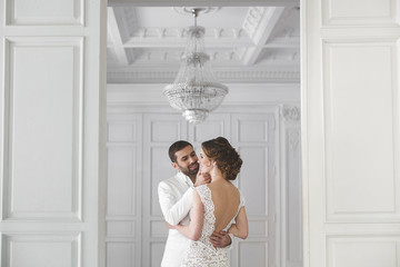 Chic wedding couple groom and bride posing in a white Studio. Happy couple laughing. White dress....