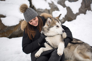 Beautiful girl in winter forest with dog. Play with the dog Siberian husky.