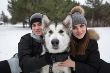 Beautiful family, a man and a girl in winter forest with dog. Play with the dog Siberian husky.