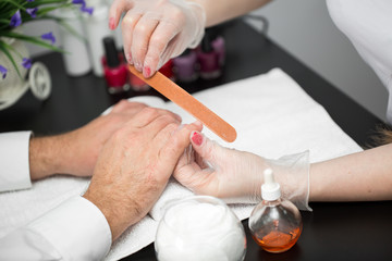 Girl manicurist doing manicure for man in beauty salon