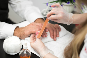 Obraz na płótnie Canvas Girl manicurist doing manicure for man in beauty salon