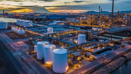 Zelfklevend Fotobehang Aerial view oil terminal is industrial facility at night for storage of oil and petrochemical products ready for transport to further storage facilities in city skyline. © Kalyakan