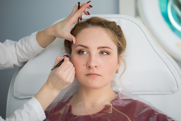 Fototapeta premium Tweezing eyebrow by beautician. Isolated.