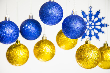 Beautiful Christmas and New Year colorful background. Close up of blue and golden shining ornaments hanging on glossy silver ropes isolated on white. Horizontal color phtography.