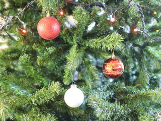 presents for christmas, red, pink, white and glass balls on the background of a green Christmas tree