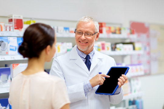 apothecary and customer with tablet pc at pharmacy