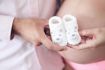 man and pregnant women holding baby shoes