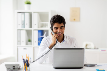 happy businessman calling on desk phone at office