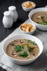 Mushroom cream soup with herbs and spices over rustic wooden background