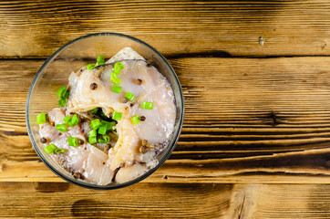 Pieces of the marinated carp in bowl on wooden table. Top view