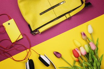 Bag, flowers and other womens accessories by color and the bright background. The view from the top. Flat lay.