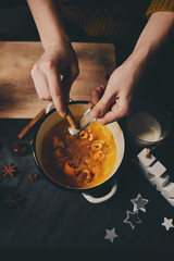 Female hands cooking orange jam for Christmas gifts