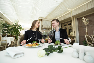 Smiling couple eating main course at restaurant
