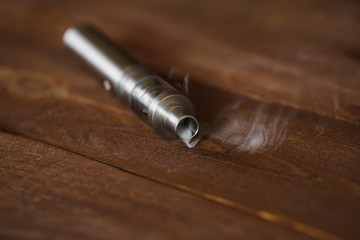 Electronic cigarette on a wooden table. Smoke.