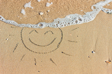 Fototapeta na wymiar Waves with foam blue sea on a sunny sandy beach in resort on summer vacation rest. Symbol of the sun drawing on the sand.