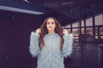 Close-up fashion portrait of gorgeous woman in stylish winter fluffy coat and posing