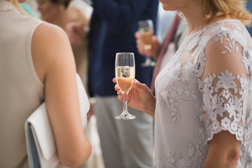 Glass of champagne on the background of a friends wedding in the hands of women.