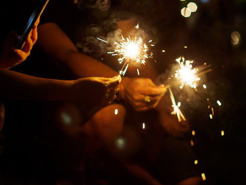 People take pictures of sparkler fireworks on their smartphones during a Thai festival at night. Pathum Thani, Thailand. Travel and New Year's celebration concept.