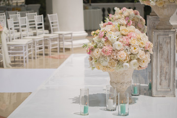 Beautiful bouquet of roses in a vase on a background of a wedding arch. Beautiful set up for the wedding ceremony.