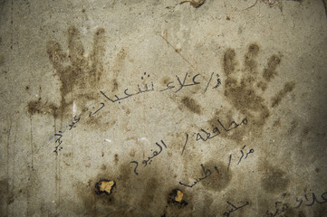 Hand prints on a wall with arabic text