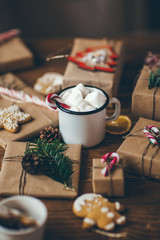 Cup of hot chocolate with marshmallows on wooden table with Christmas gifts 