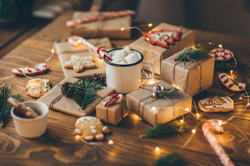 Cup of hot chocolate with marshmallows on wooden table with Christmas gifts 